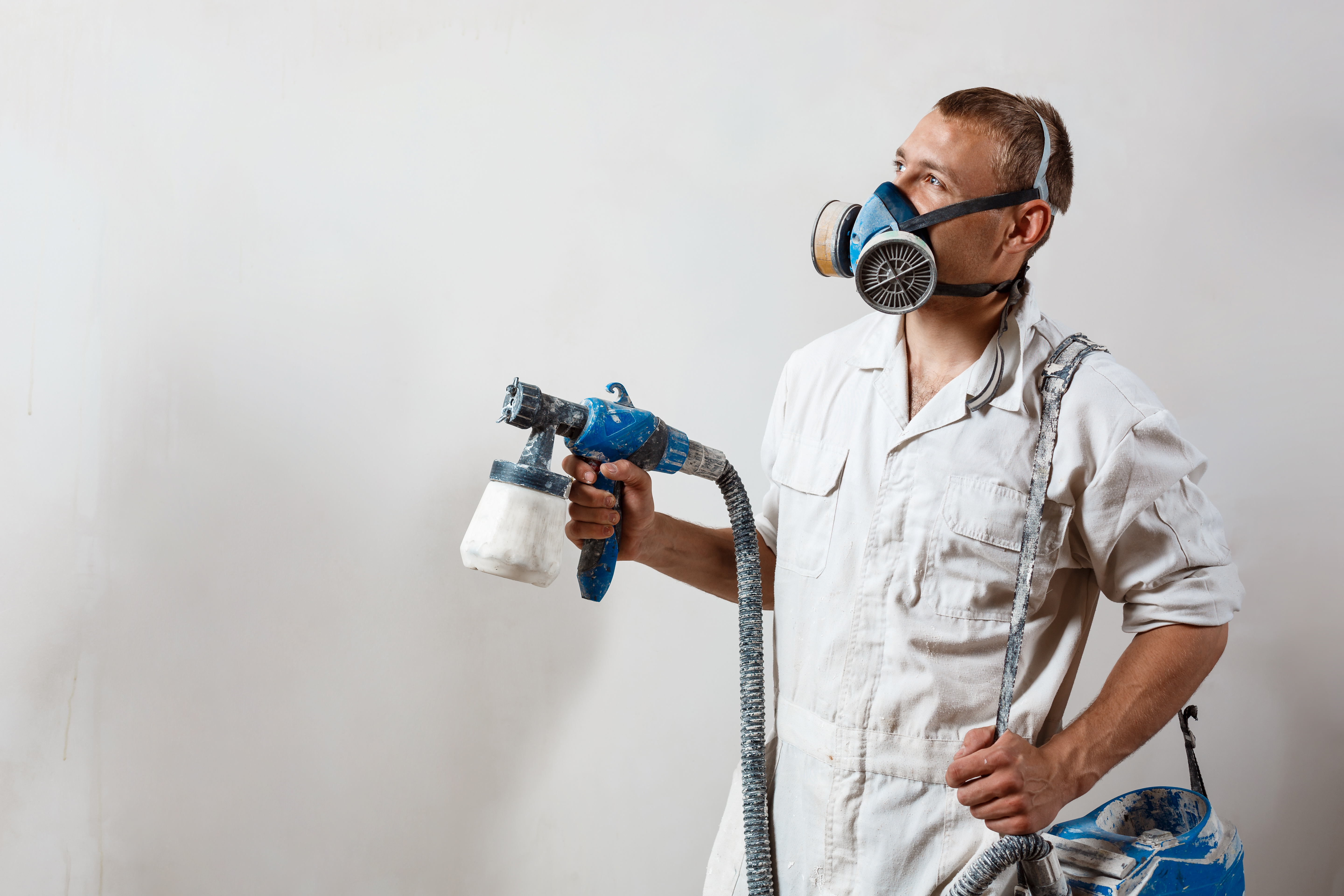 Worker painting wall with spray gun in white color. Worker painting wall with spray gun in white color. Copy space.